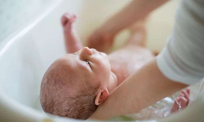 Mama kąpiąca niemowlę w wanience
