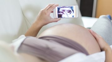 Kobieta w ciąży przegląda treści na telefonie komórkowym