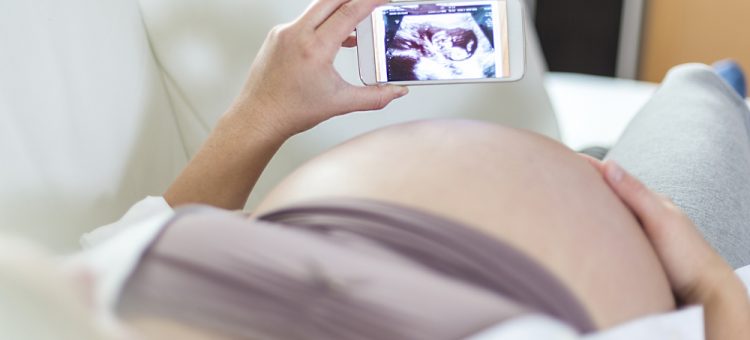 Kobieta w ciąży przegląda treści na telefonie komórkowym