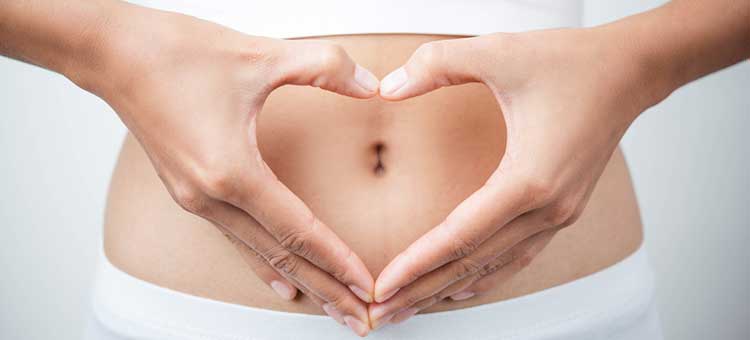Ręce w kształcie serca przed brzuchem matki w 8. tygodniu ciąży