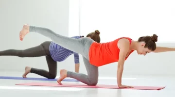 Dwie młode kobiety w ciąży wykonują ćwiczenia relaksacyjne na macie do ćwiczeń