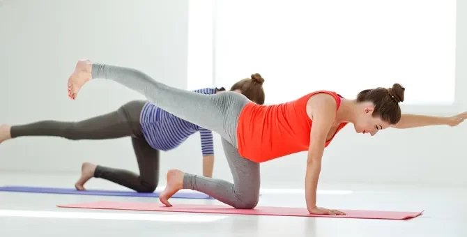 Dwie młode kobiety w ciąży wykonują ćwiczenia relaksacyjne na macie do ćwiczeń