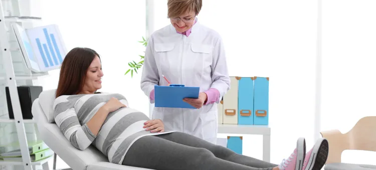 Uśmiechnięta kobieta w ciąży na łóżku w gabinecie oraz lekarka analizująca wyniki