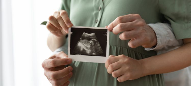 kobieta w ciąży oraz partner trzymający wspólnie zdjęcie usg
