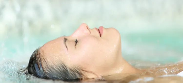 Kobieta w basenie relaksuje się, leżąc na plecach na wodzie