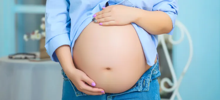 Kobieta w ciąży trzyma ręce na brzuchu, zbliżenie na ręce i brzuch