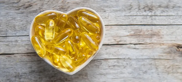 Żółte kapsułki omega 3 w kształcie serca na drewnianej powierzchni