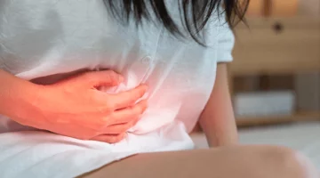 Kobieta trzymająca się za podbrzusze z powodu bólu po porodzie, który może wskazywać na zapalenie błony śluzowej macicy.