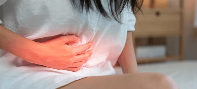 Kobieta trzymająca się za podbrzusze z powodu bólu po porodzie, który może wskazywać na zapalenie błony śluzowej macicy.