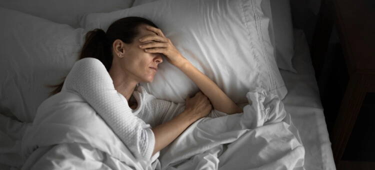 Kobieta leżąca w łóżku z objawami osłabienia i bólu po porodzie, które mogą świadczyć o infekcji połogowej.