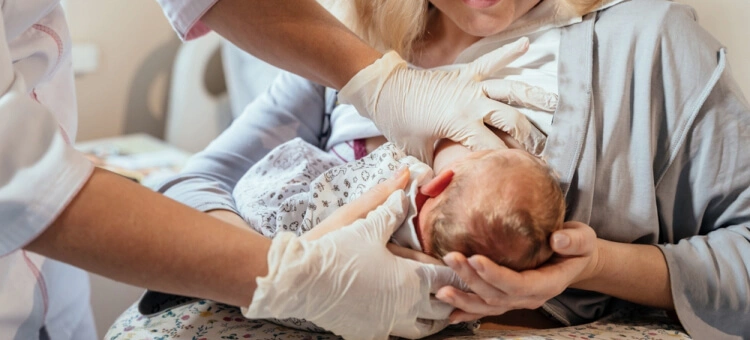Na co należy zwrócić uwagę podczas karmienia piersią? Położna pomagająca mamie karmić po porodzie dziecka