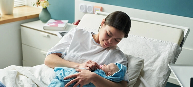 Krwotok porodowy po cięciu cesarskim – co dzieje się w przypadku krwotoku po cesarskim cięciu? Krwotok poporodowy – mama z noworodkiem na łóżku szpitalnym