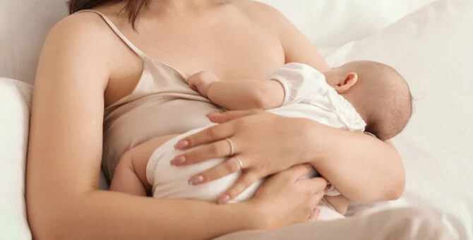Mama karmiąca niemowlę w pozycji naturalnej półleżącej
