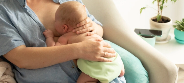 Pozycja wyprostowana Niemowlę pijące mleko mamy w pozycji wyprostowanej jak koala