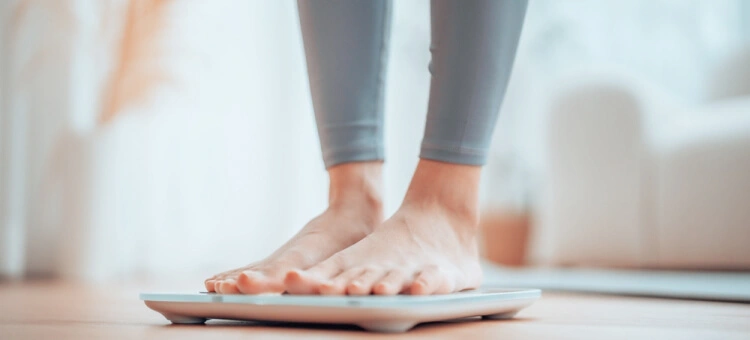 Kobieta w ciąży ważąca się na wadze