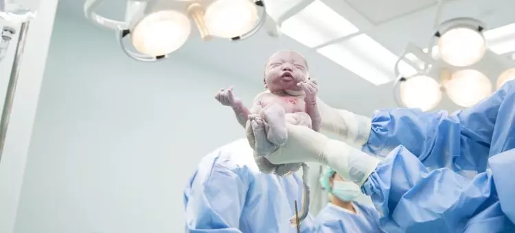 Lekarz trzymający dziecko tuż po porodzie, zbliżenie na noworodka i ręce