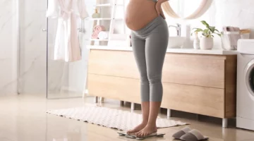 Kobieta w ciąży ważąca się na wadze w łazience