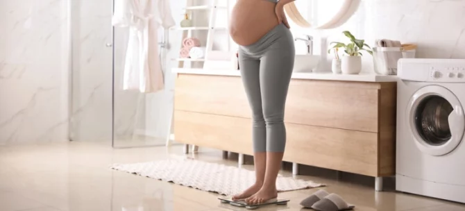 Kobieta w ciąży ważąca się na wadze w łazience