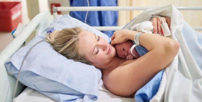 Mama leżąca na łóżku szpitalnym po porodzie