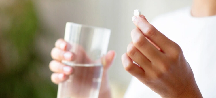 Leki a karmienie piersią: antybiotyki, paracetamol, ibuprofen Kobieta popijająca ibuprofen szklanką wody