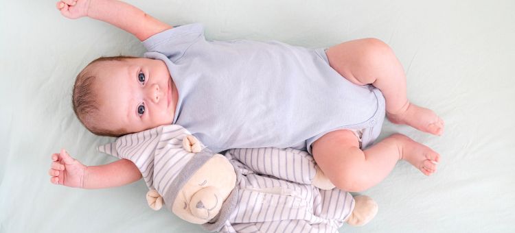 Nowonarodzony chłopiec w wieku 3 miesięcy leży w łóżeczku dziecięcym z misiem