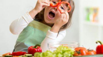 Dziewczynka w kuchni jedząca warzywa