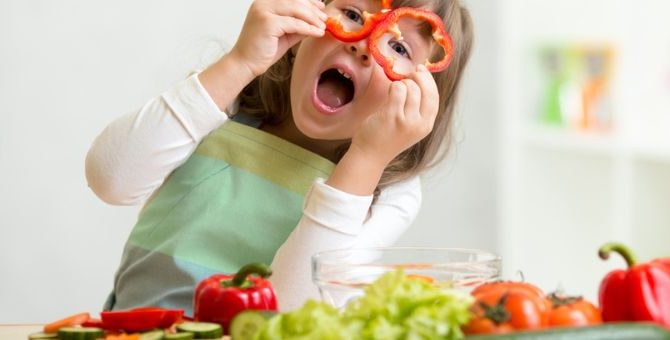 Dziewczynka w kuchni jedząca warzywa