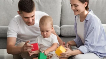 Mama i tata bawiący się z rocznym dzieckiem na dywanie.