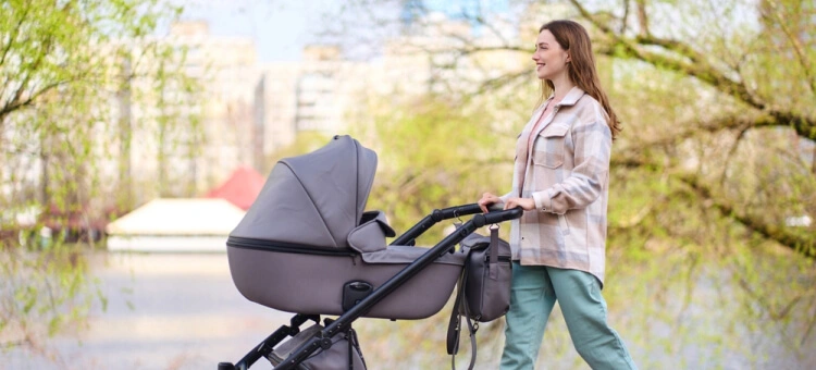 Mama spacerująca z dzieckiem w wózku po parku