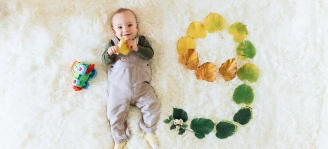 Niemowlę leżące na dywanie z numerem 9. miesiąca życia