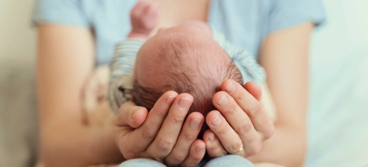 Mama usypiająca nowordoka na rękach