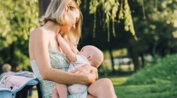 Mama karmiąca niemowlę na ławce w parku