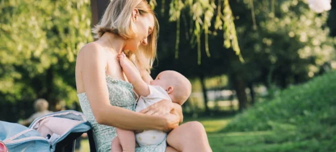 Mama karmiąca niemowlę na ławce w parku