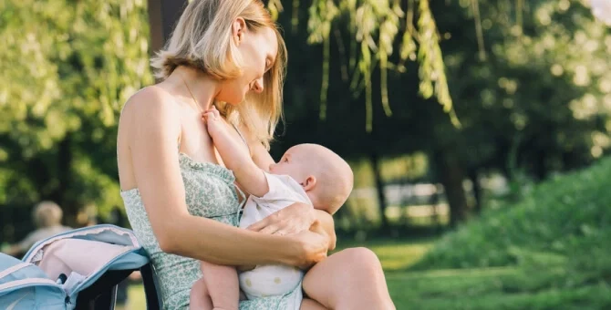 Mama karmiąca niemowlę na ławce w parku