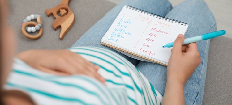Kobieta w ciąży z listą imion siedząca na sofie