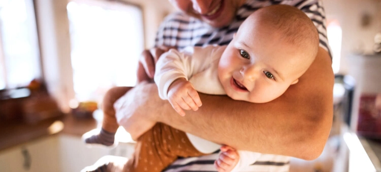Niemowlę noszone blisko ciała rodzica z prawidłowym podtrzymaniem głowy i tułowia