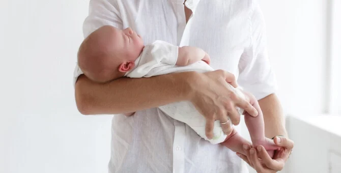 Prawidłowe noszenie noworodka na rękach z podparciem główki i pleców