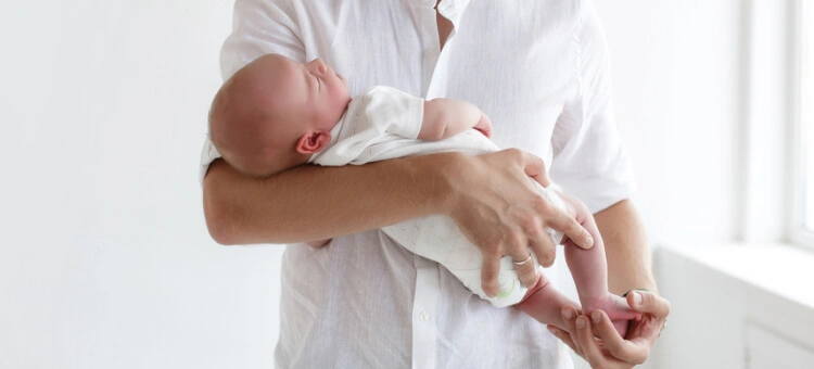 Prawidłowe noszenie noworodka na rękach z podparciem główki i pleców