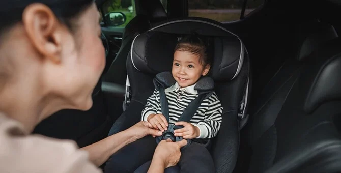 Mama zapinająca dziecko w foteliku samochodowym