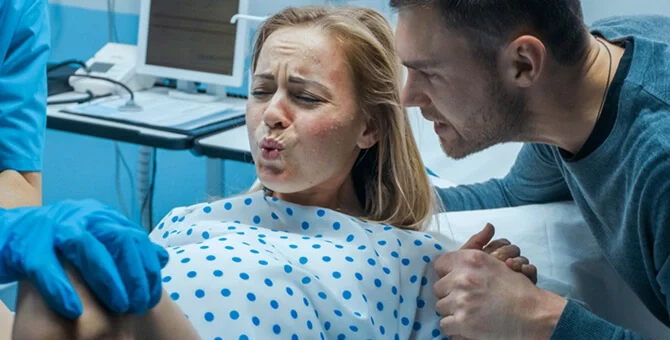 Kobieta wykonująca wydech podczas skurczu porodowego