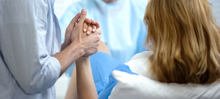 Partner trzymający rodzącą kobietę za rękę