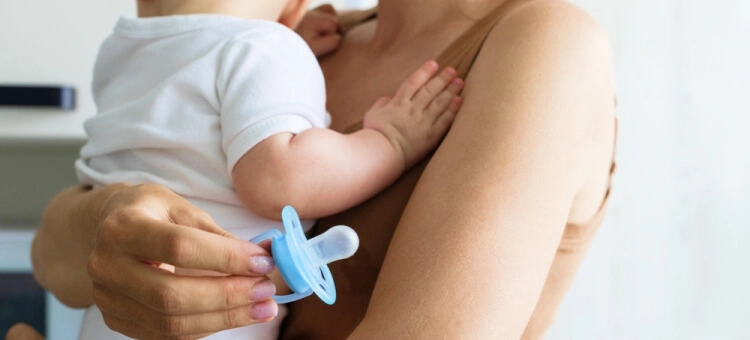 Niemowlę na rękach u mamy czekające na smoczek