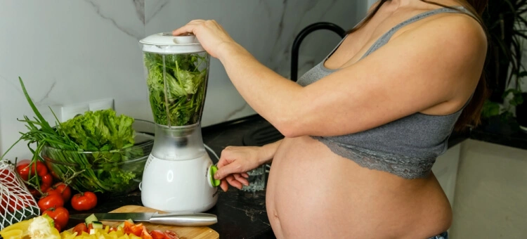 Mama w ciąży robiąca świeży sok z warzyw i owoców