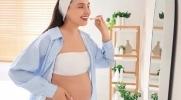 Kobieta w ciąży szczotkująca zęby w łazience