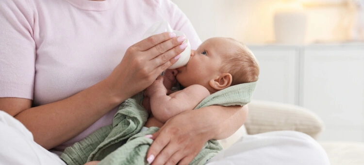 Mama karmiąca noworodka butelką w bezpiecznej, półleżącej pozycji