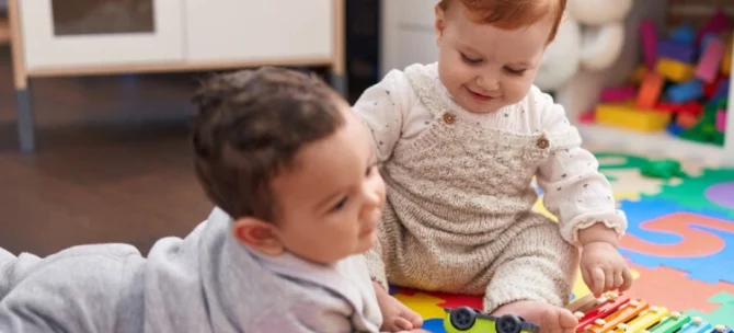 Niemowlęta w żłobku bawiące się na macie
