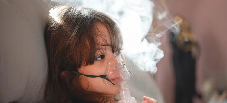 Ranking nebulizatorów 2026 – na co zwrócić uwagę przy wyborze? Dziewczynka podczas inhalacji z użyciem nebulizatora