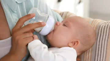 Niemowlę pijące mleko z butelki – wybór odpowiedniej butelki dla noworodka