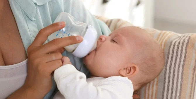 Niemowlę pijące mleko z butelki – wybór odpowiedniej butelki dla noworodka