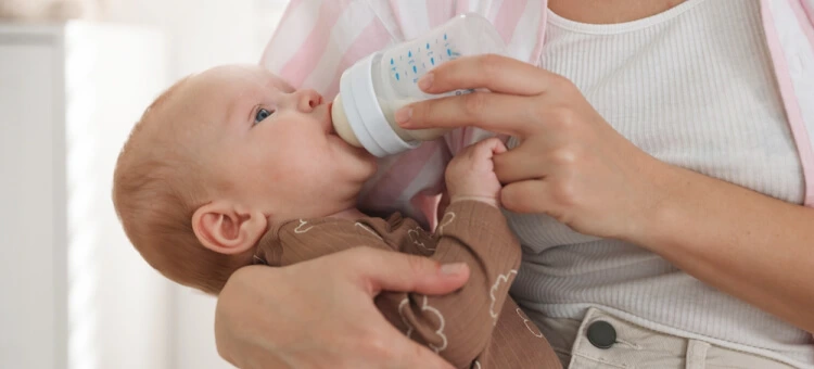 Mama karmiąca niemowlę mlekiem z butelki – pierwsza butelka do karmienia noworodka